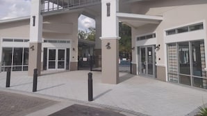 Um edifício moderno com entrada coberta, janelas amplas e um caminho pavimentado.