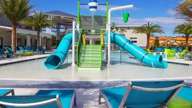 Parque aquático com duas escorregas e área de piscina com espreguiçadeiras.