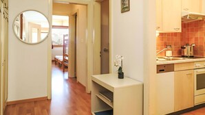A hallway with a wooden floor, a small white shelf with a potted orchid, and a mirror on the wall. - Rosablanche A24 by Interhome (Siviez-Nendaz)