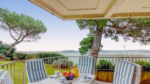 Eine Terrasse mit Tisch für zwei Personen, gestreifte Stühle und Blick auf das Meer.