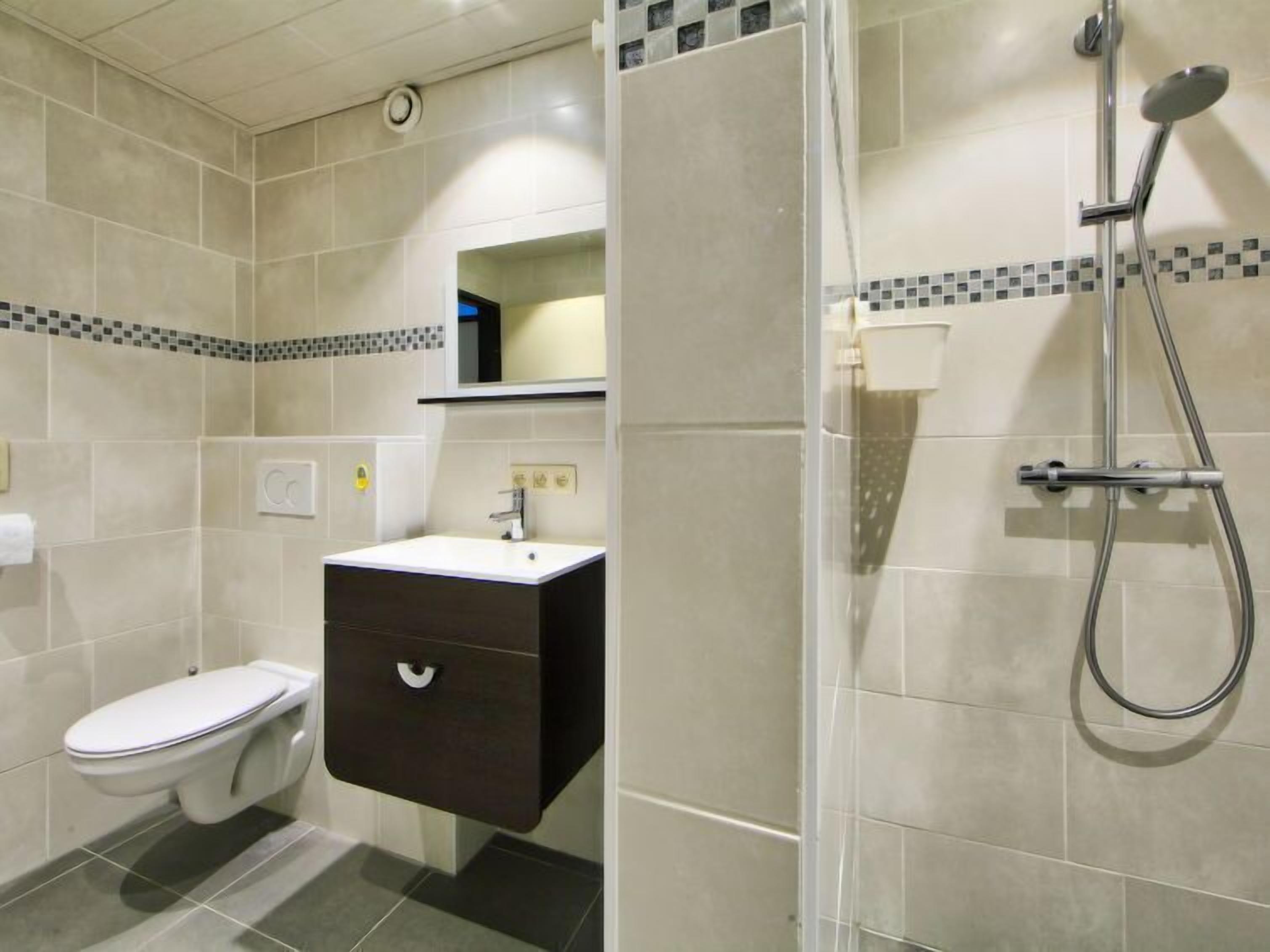 A bathroom with a toilet, a sink with a dark cabinet, and a shower area.