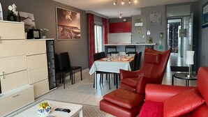 A modern living room with a dining area, featuring a sofa, a coffee table, and a dining table set for four.