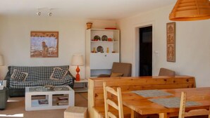 A cozy living room with a checkered sofa, a wooden dining table, and a white side table. - Bel Alp D3 by Interhome (Nendaz)