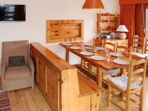 A dining area with a wooden table set for four, surrounded by wooden chairs.