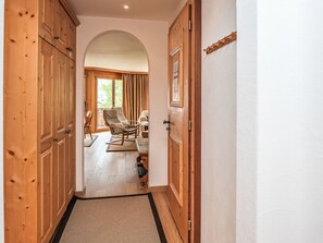 Un couloir avec des portes en bois, un tapis, un fauteuil à bascule et un canapé.