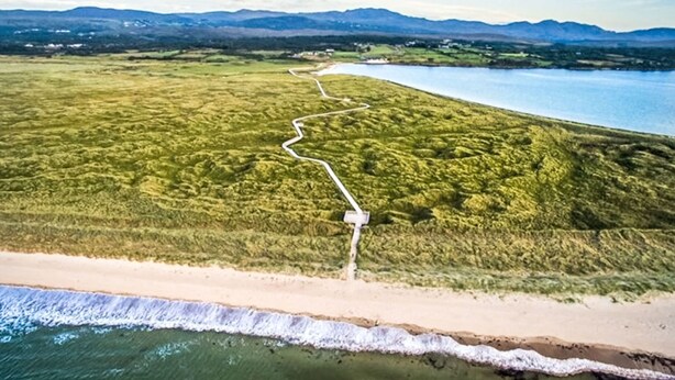 An aerial view of a coastal landscape with a winding path leading to a beach.