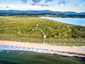Vue aérienne d’un paysage côtier avec un sentier sinueux menant à une plage.