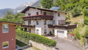 Un edificio de dos plantas con balcones, un garaje y un panel solar.
