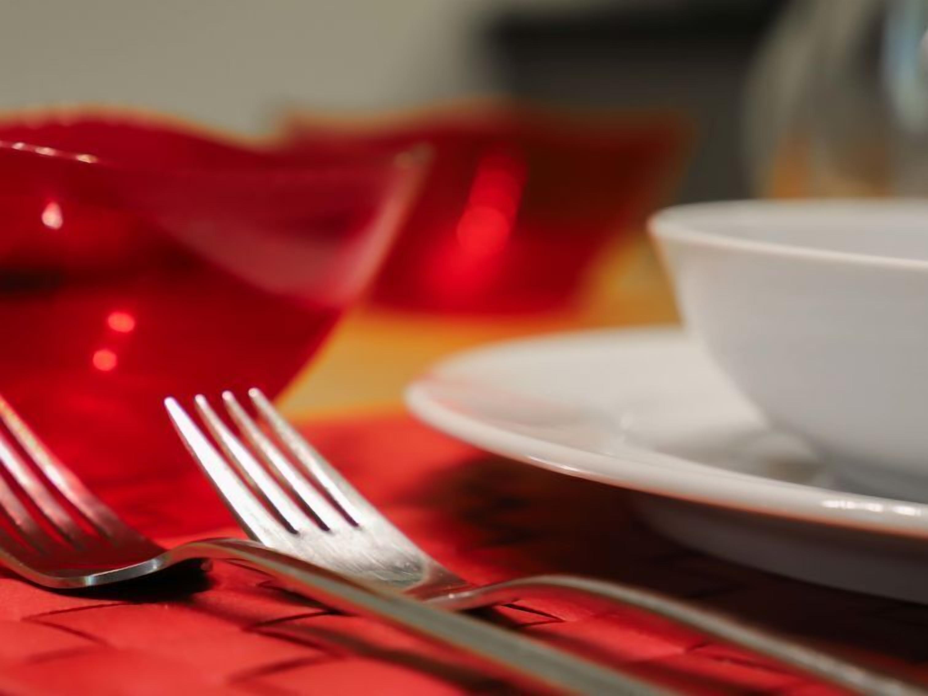 A dining table with a white plate and a fork.