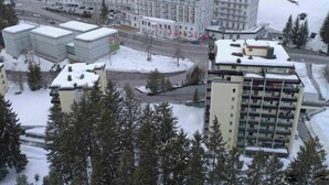 A large, multi-story building with a symmetrical facade, surrounded by snow-covered terrain and trees.