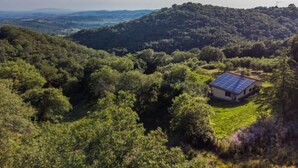 Una casa amb teulada solar rodejada de bosc dens i turons.