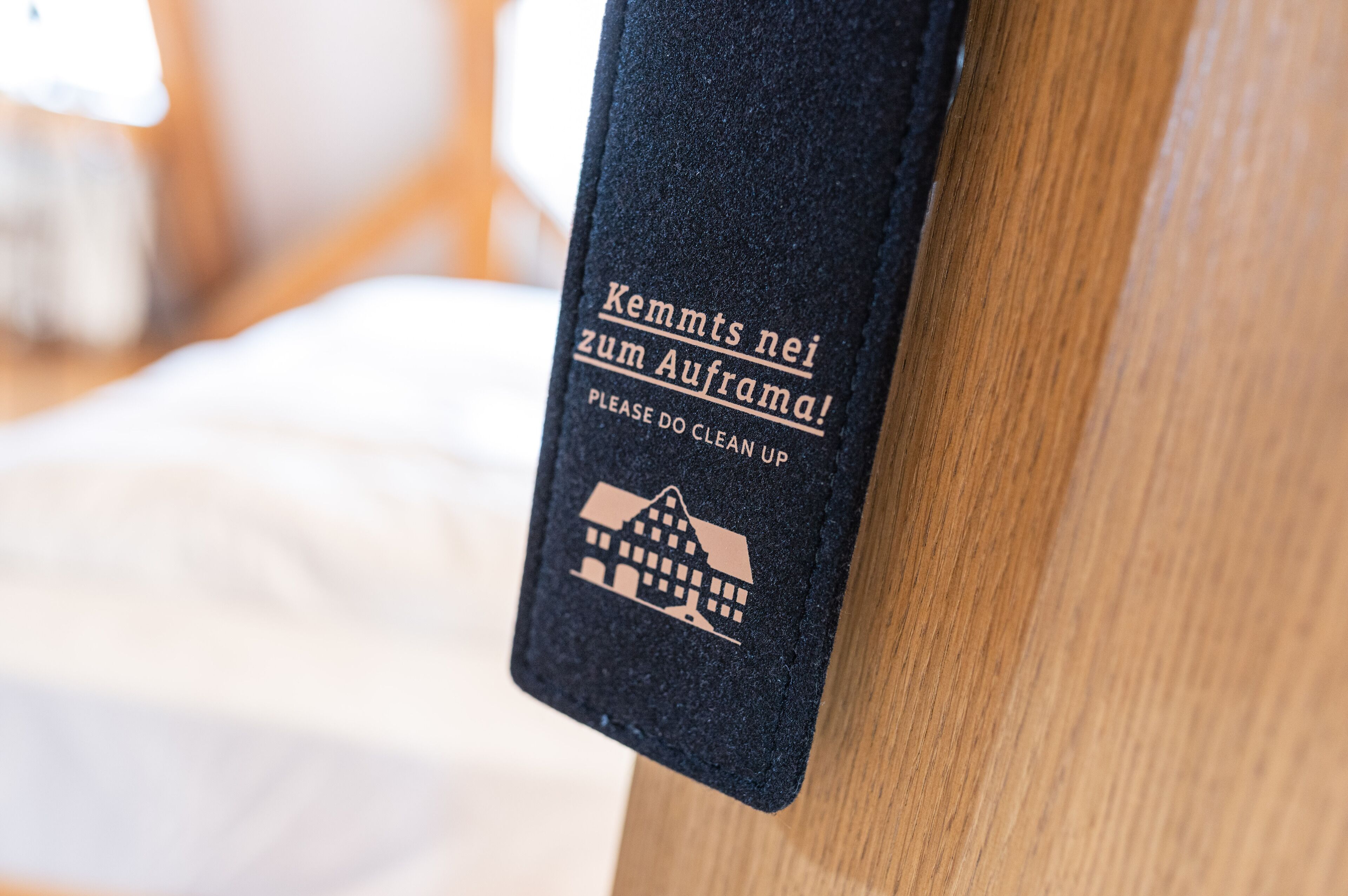 A close-up of a black doormat with text in German and an icon of a building.