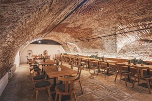 A rustic interior with stone walls and wooden tables and chairs. - Romantik Hotel Alte Posthalterei (Zusmarshausen)