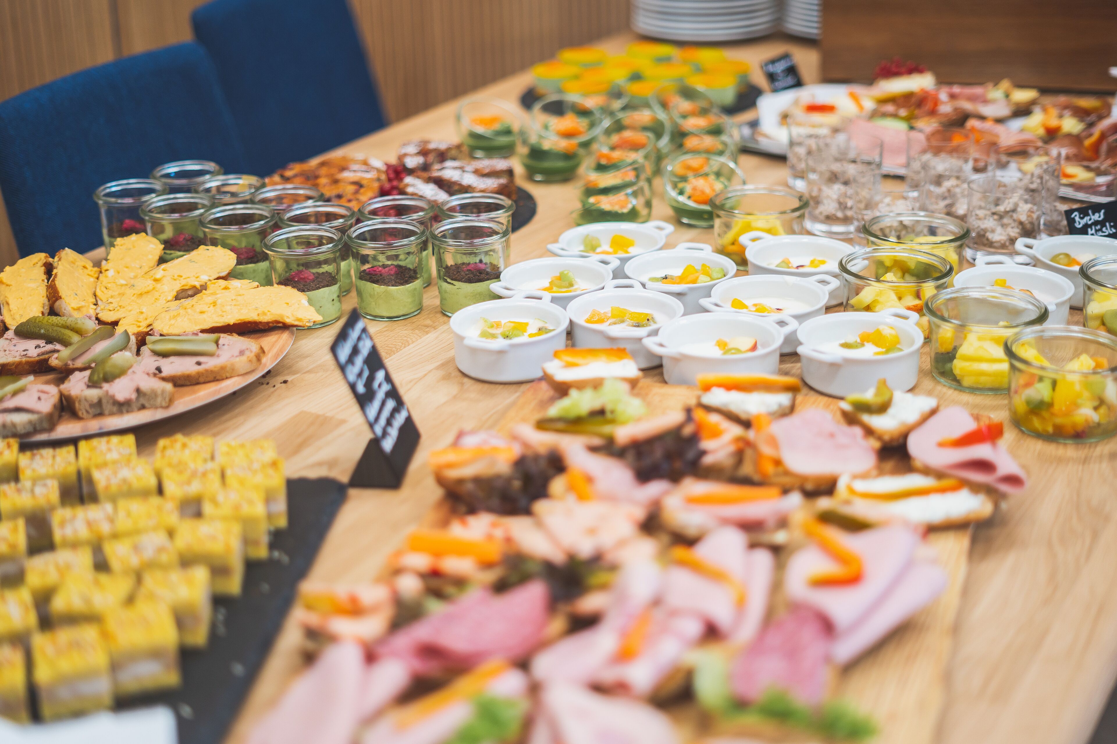 Une table de buffet proposant une variété de plats, notamment des viandes, des fromages et des desserts.