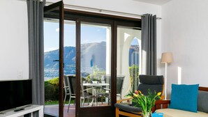 Une chambre d’hôtel moderne équipée d’une télévision, d’un canapé, d’une table basse et d’un coin repas avec une table et des chaises.