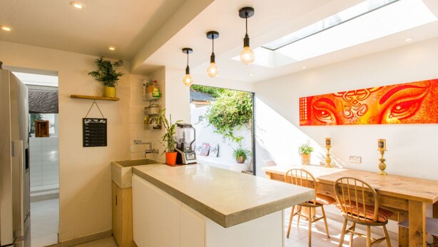 A modern kitchen with a central island, built-in appliances, and a dining area with a wooden table and chairs. - Luxury 4BDR cottage right in the heart of Brighton (Brighton)