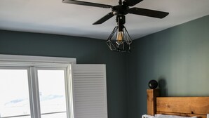 A bedroom with a wooden bed, a ceiling fan, and a view of the outdoors through a window. - Luxury 4BDR cottage right in the heart of Brighton (Brighton)