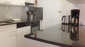 Una cocina moderna con gabinetes blancos, una campana extractora de acero inoxidable, un lavavajillas y una cafetera.