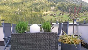 A balcony with wicker furniture, potted plants, and a view of a mountainous landscape. - Schaller by Interhome (See)