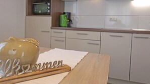 A kitchen with white cabinets, a wooden countertop, a green apple on a shelf, and a ceramic jug with the word "Bremen" on it. - Schaller by Interhome (See)