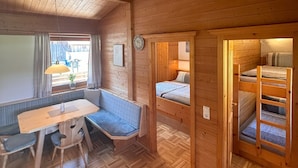 Ein gemütliches Blockhaus-Interieur mit einer Sitzecke mit Holzbank, einem Tisch und einem Bett mit einer Leiter.