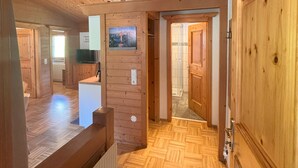 Ein Holzinterieur mit Fischgrätparkett, einer Holztür und einem kleinen Bild an der Wand.