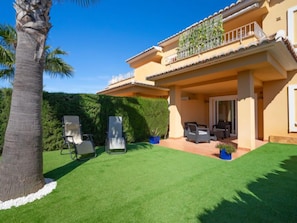 A two-story house with a covered patio, outdoor seating, and a well-maintained lawn.