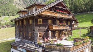 A wooden chalet with a balcony, outdoor seating, and a mountain backdrop. - Beim Holzschnitzer by Interhome (Sölden)