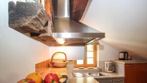 A kitchen with a stainless steel range hood, a sink, a toaster, and a tray with apples and an orange. - Beim Holzschnitzer by Interhome (Sölden)