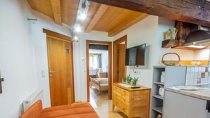 A bedroom with a wooden ceiling, a wooden dresser, a television, and a kitchen area with a sink and cabinets. - Beim Holzschnitzer by Interhome (Sölden)