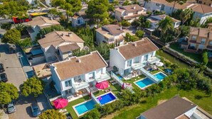 Un barrio residencial con una casa grande, piscina y un porche cubierto.