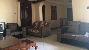 A living room with a sofa, armchairs, a coffee table, and a television.