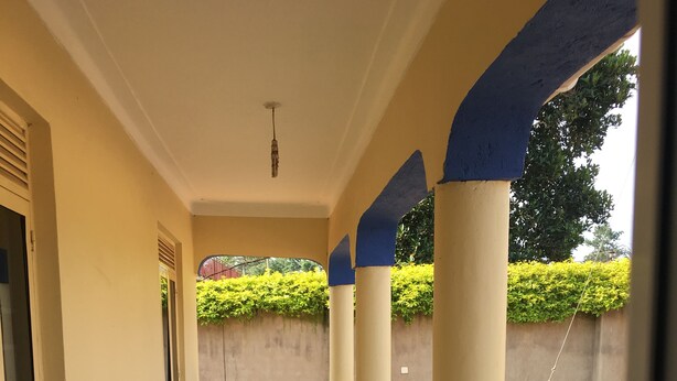 A corridor with tiled flooring, blue balustrades, and a bench.