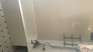 A bathroom with white tiled walls, a bathtub, and a shower area with a handheld showerhead.