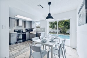 A modern kitchen with grey cabinets, a built-in oven, and a dining area with a white table set for six. - 2BR Home w/ Private Pool & 2 King Beds / Near Springs (Port Richey)