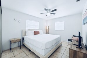 A bedroom with a bed, bedside table, nightstand, ceiling fan, and a TV on a wooden stand. - 2BR Home w/ Private Pool & 2 King Beds / Near Springs (Port Richey)