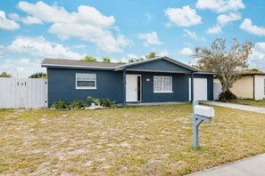 A single-story house with a dark blue exterior, a front door, and a mailbox. - 2BR Home w/ Private Pool & 2 King Beds / Near Springs (Port Richey)