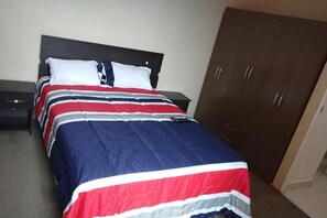 A bed with a striped bedspread, a wooden headboard, and a wardrobe with three doors. - Moderno y Acogedor  3 Habitaciones  Cerca del Centro Histórico de Lima (Cercado de Lima)