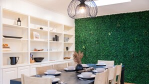 A dining area with a dark table, white chairs, and a green wall. - Longhorn Getaway in Dripping springs (Dripping Springs)