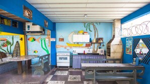 Una cocina con estufa, microondas y un mural con motivos de plátanos.