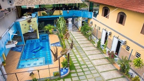Un patio con piscina, plantas en macetas y suelo de baldosas.