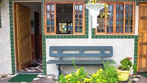 Entrada de un edificio con puerta de madera, banco y plantas en macetas.