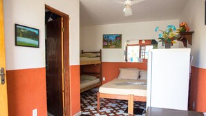 Una habitación pequeña con una cama litera, un refrigerador y piso de baldosas.