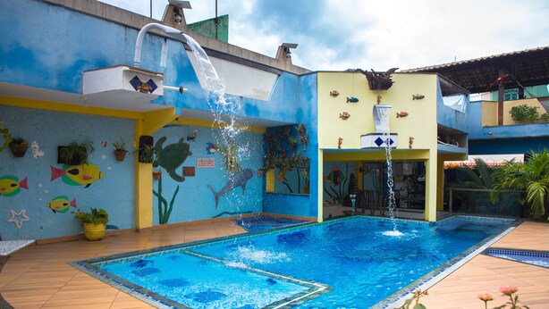 Una piscina con una cascada, rodeada por un mural lleno de peces y criaturas marinas.