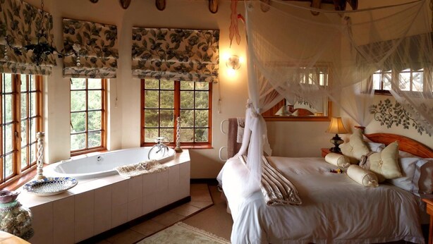 A bedroom with a large bed, a bathtub, and a canopy bed. - Otters Den Self Catering Cottages (Fort Nottingham)