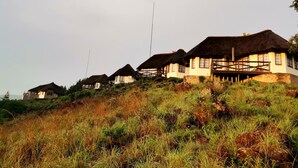 A row of traditional houses with thatched roofs, situated on a grassy hillside. - Otters Den Self Catering Cottages (Fort Nottingham)