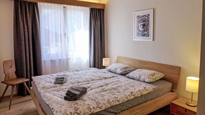 A neatly made bed with floral bedding, a wooden headboard, and a bedside lamp. - Chalet Almis-Bödeli by Interhome (Grindelwald)