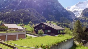 A mountain house with a view of snow-capped peaks, surrounded by greenery and a clear sky. - Chalet Almis-Bödeli by Interhome (Grindelwald)