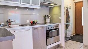 A modern kitchen with a stainless steel stove, a built-in oven, and a large window above the sink. - Chalet Almis-Bödeli by Interhome (Grindelwald)