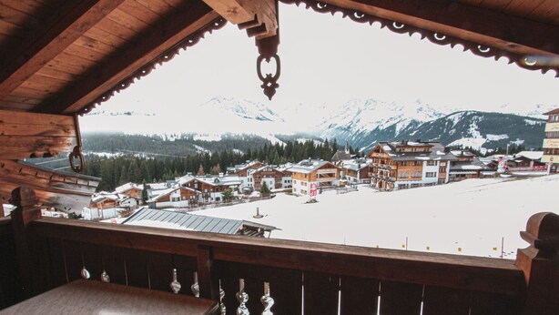 A wooden balcony with a view of a snowy mountain town. - Voithofer by Interhome (Königsleiten)